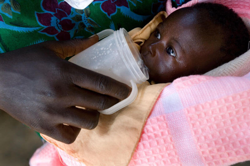 A young infant being cup fed with a mug in Kenya. Photo: PATH/Evelyn Hockstein