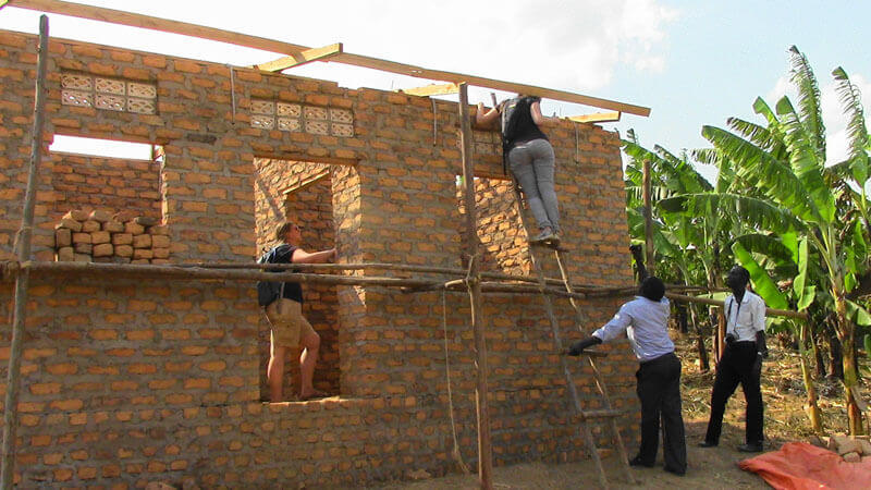 Two Global Health Fellow program-sponsored interns help build a house for an HIV expectant mother in Uganda. Photo: Global Health Fellows Program II/PHI