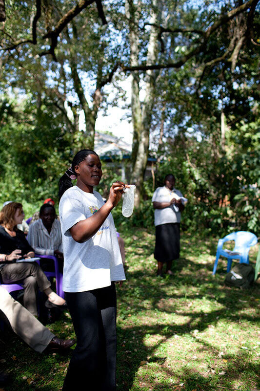 A woman demonstrates use of a female condom at a community meeting in Kenya. Photo: PATH/Eric Becker