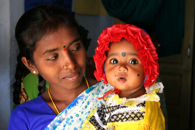 A mother holds her baby wearing a red bonnet. 